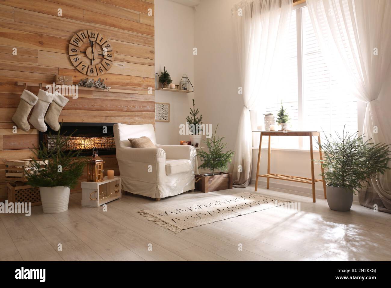 Potted fir trees and Christmas decorations in room with fireplace ...