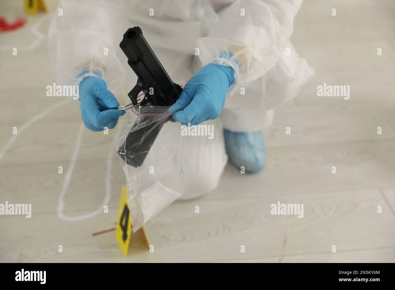 Investigator in protective suit working at crime scene indoors, closeup Stock Photo