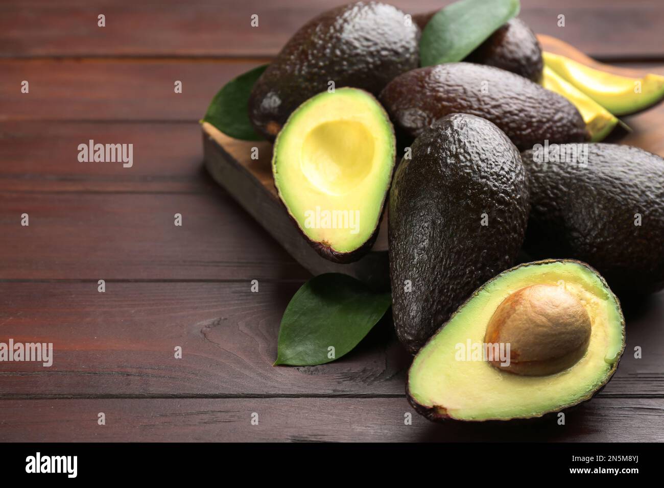 Whole and cut avocados on wooden table. Space for text Stock Photo - Alamy