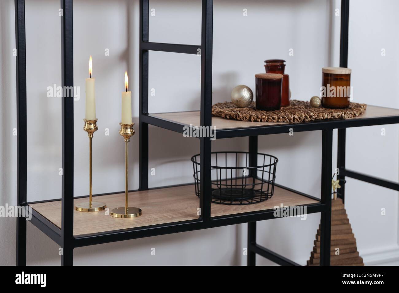 Stylish shelving unit with burning candles and decor near white wall ... - Whimsical Shelving Units With Pendant Lights