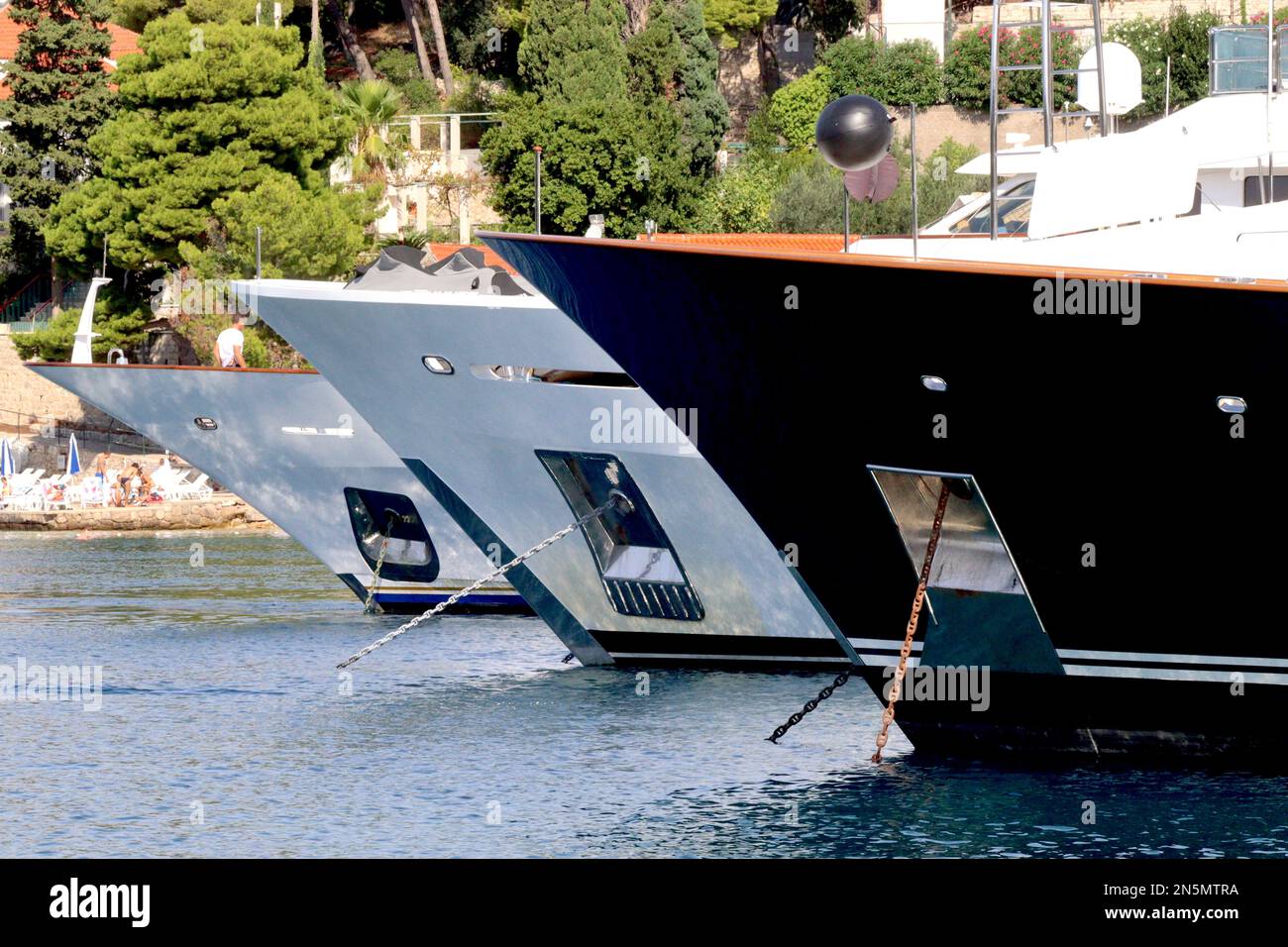 A lineup of the bows of three superyachts moored in Cavtat harbour, popular playground for owners of these vessels September 2022. Stock Photo