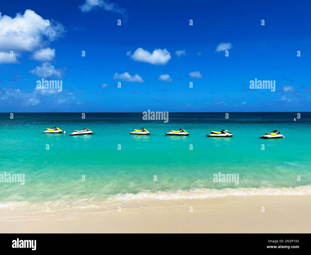 personal watercraft lined-up in the water, just off the beach, Eagle Beach, Aruba Stock Photo