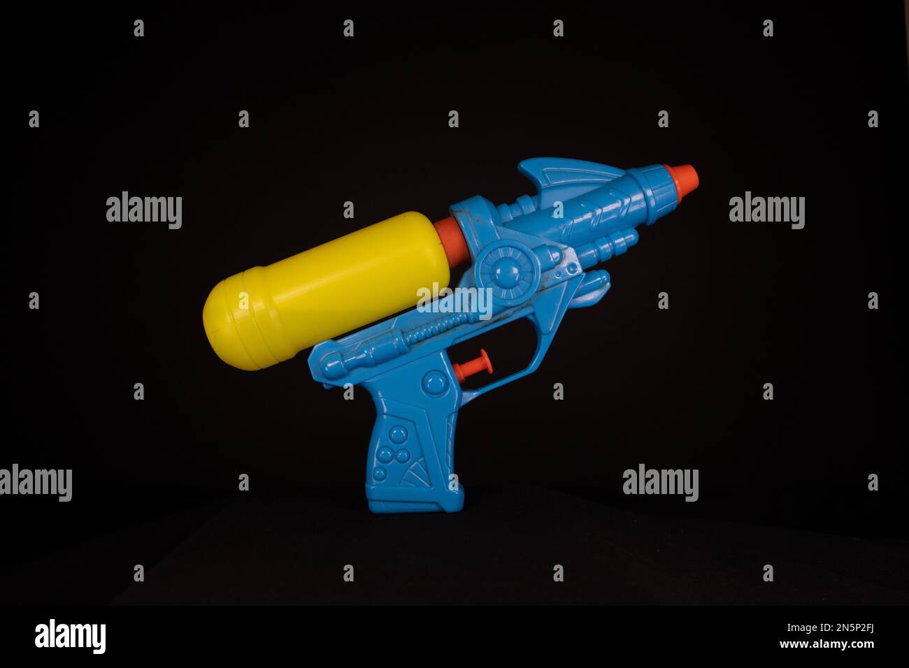 Blue and yellow children's plastic refillable water pistol isolated on a black background Stock Photo