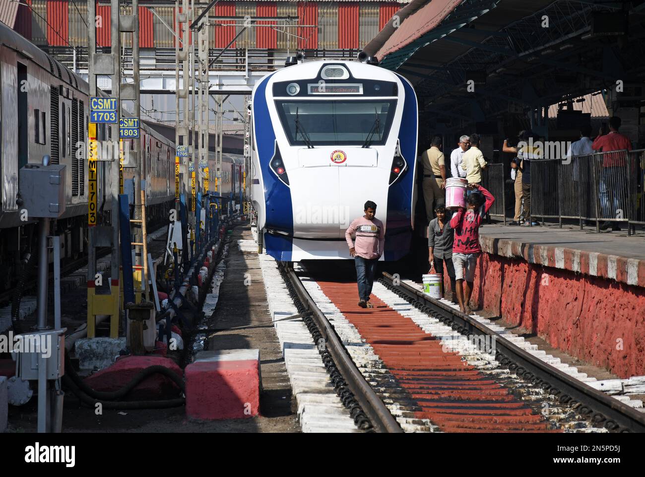 Workers paint railway tracks next to the vande bharat express stationed
