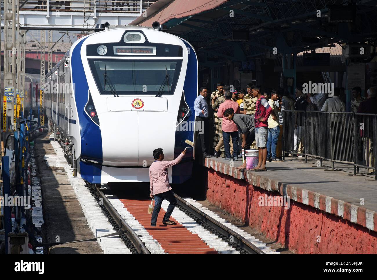 Workers paint railway tracks next to the vande bharat express stationed