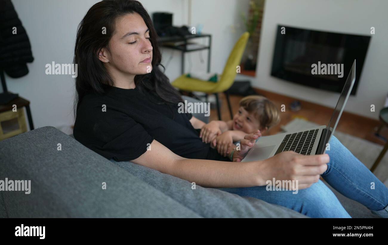 Child interrupting mother working from home in front of laptop. Parent ...