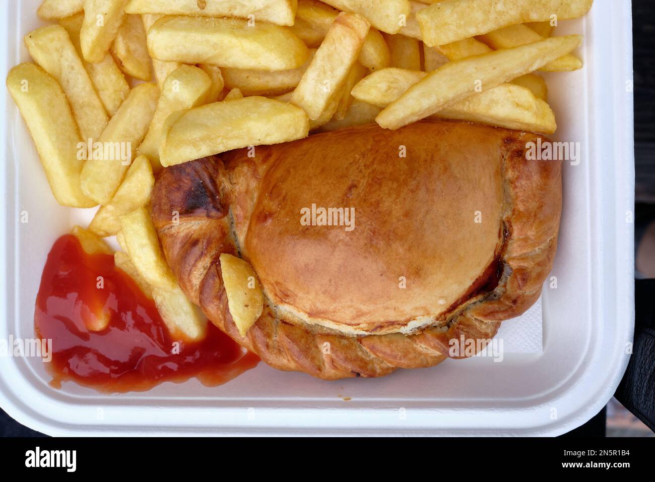 Authentic cornish pasty served with thick cut chips and ketchup in take-out tray Stock Photo
