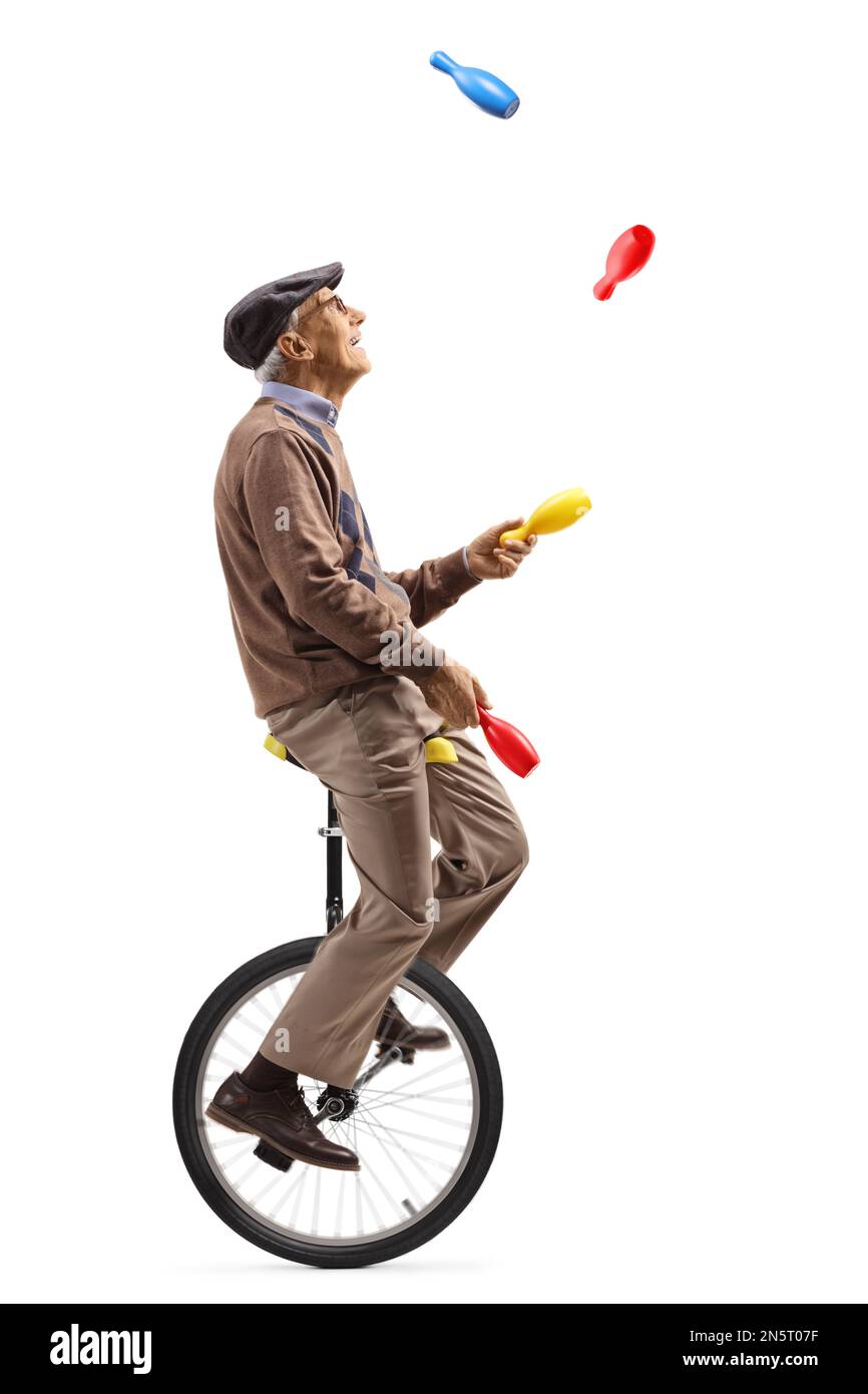 Senior man riding a unicycle and juggling isolated on white background