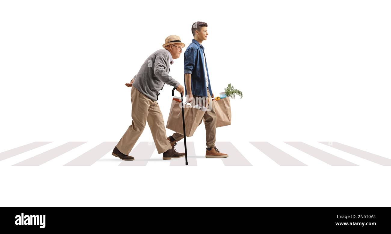 Full length profile shot of a young man helping a senior with grocery bags on a pedestrian crossing isolated on white background Stock Photo