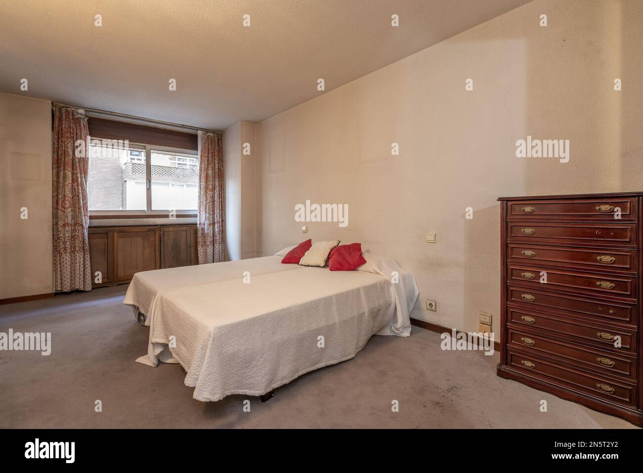 Bedroom with two single beds together and a dresser with many wooden