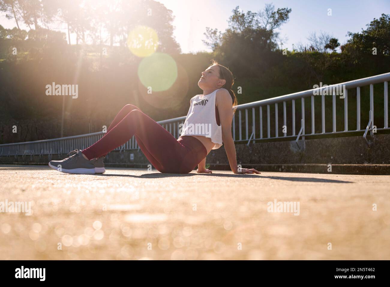 Sporty woman runner sitting on the road recovering after jogging Stock Photo