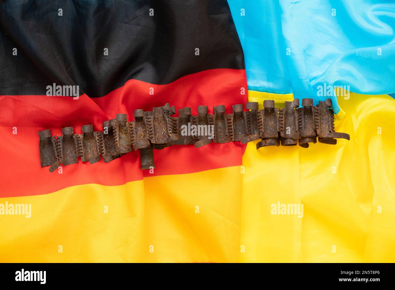 A torn Russian cartridge belt lies on two flags of Ukraine and Germany, ammunition and war Stock Photo