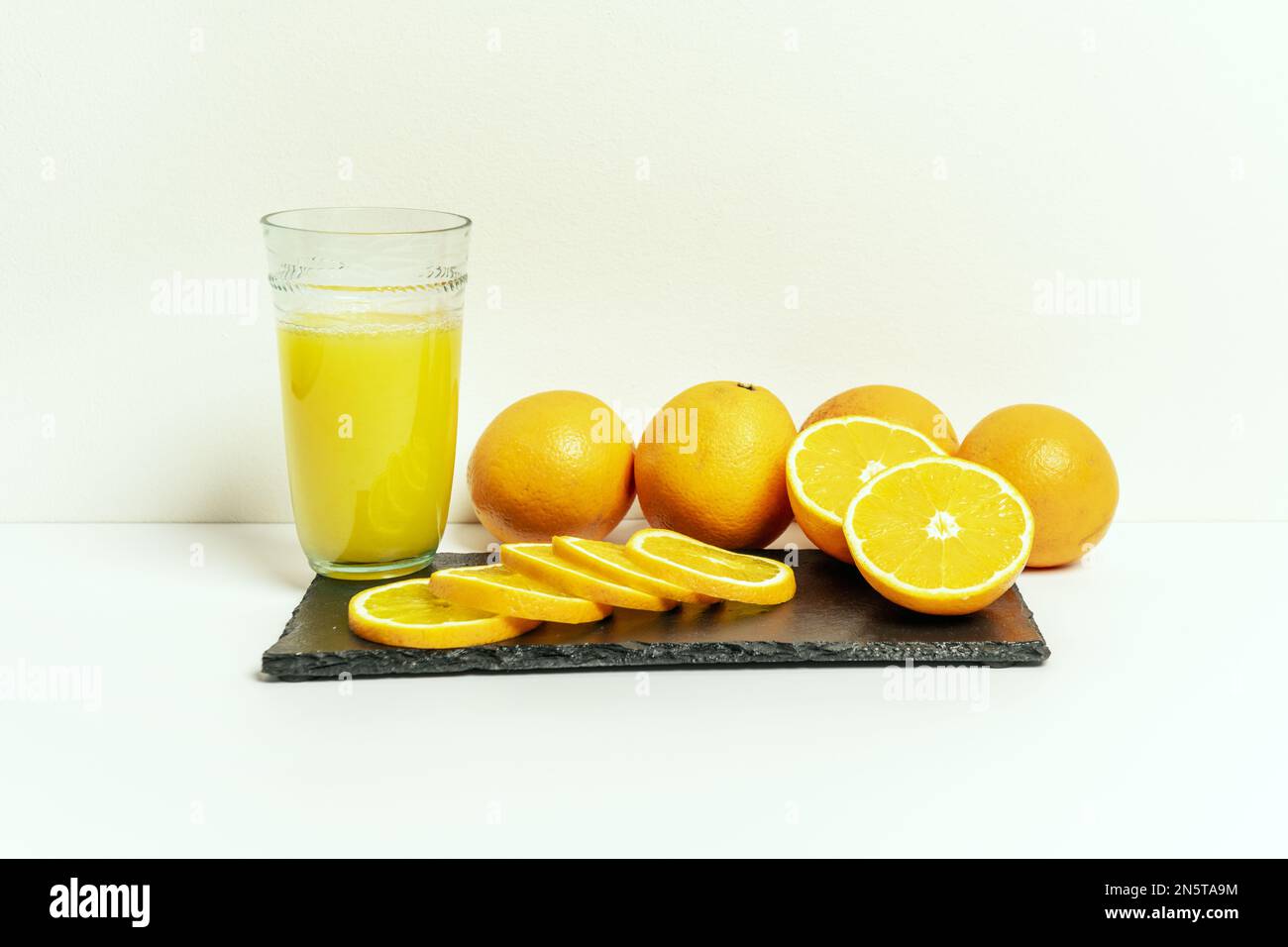 A bunch of oranges on a blackboard and next to a glass of juice Stock ...