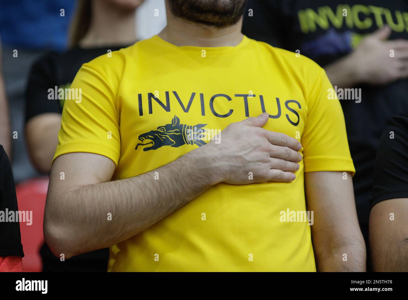 Bucharest, Romania -February 9, 2023: Details with a man wearing an Invictus Team Romania tshirt holding the right hand to his heart while listening t Stock Photo