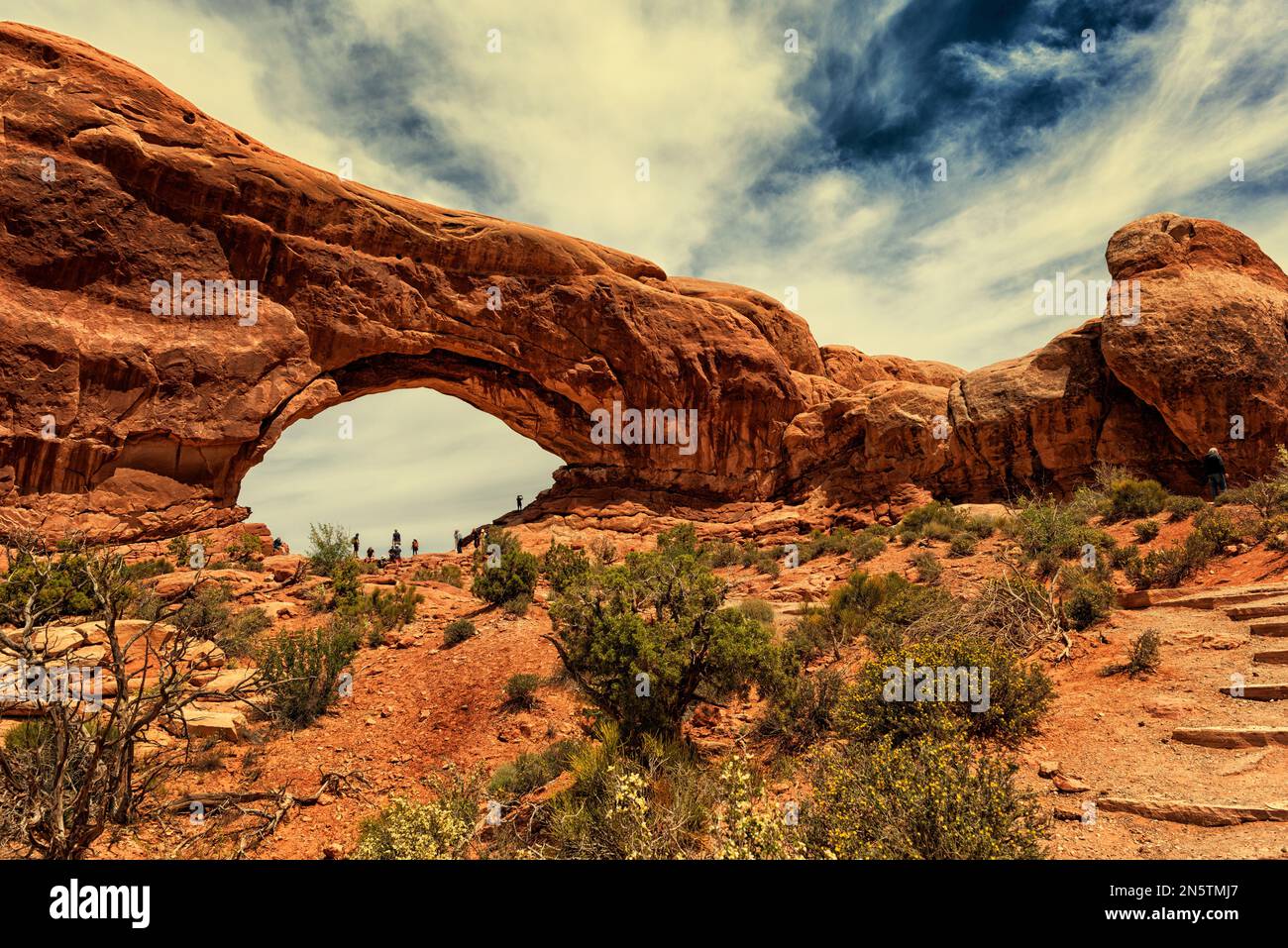 The stone arches with steps going up the rocks side and trees along the ...