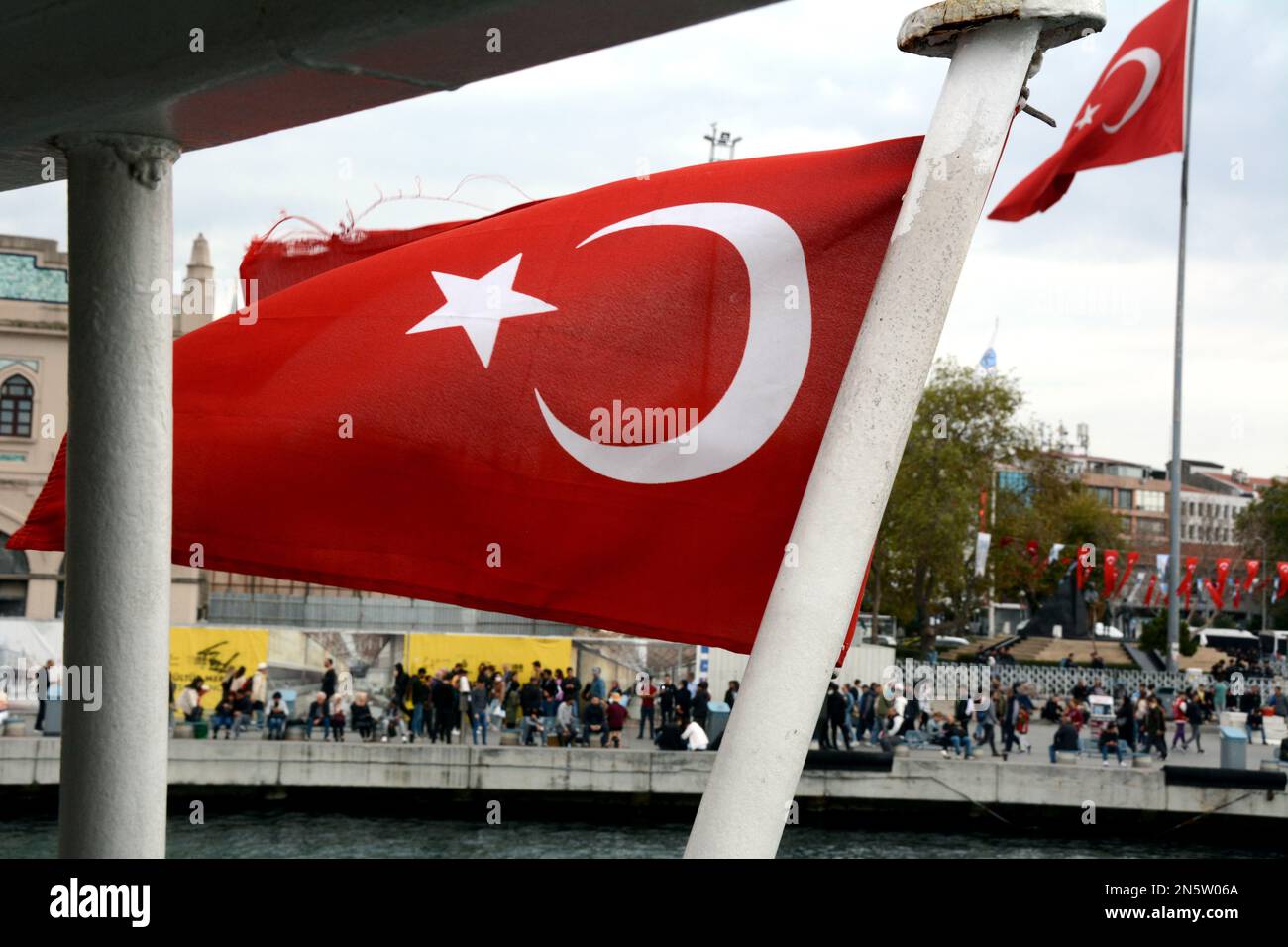 A pair of Turkish flags waving in the wind at the Kadikoy ferry station terminal and port on the Asian side of Istanbul, in Turkey. Stock Photo