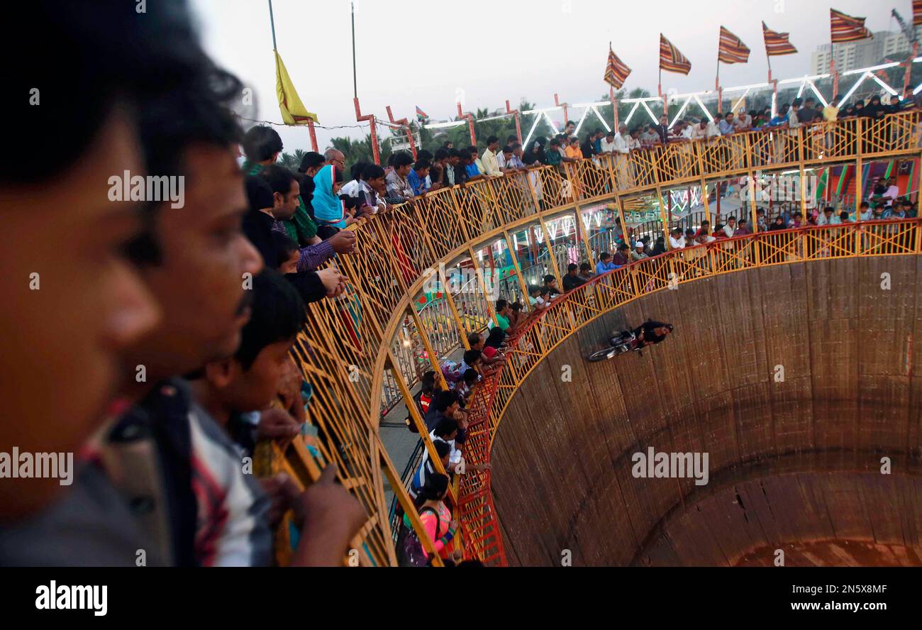 Indian people watch a daredevil perform in a “Wall of Death” at the Mahim  fair in Mumbai, India, Tuesday, Dec. 24, 2013. Devotees throng the ten  day-long fair that is held in