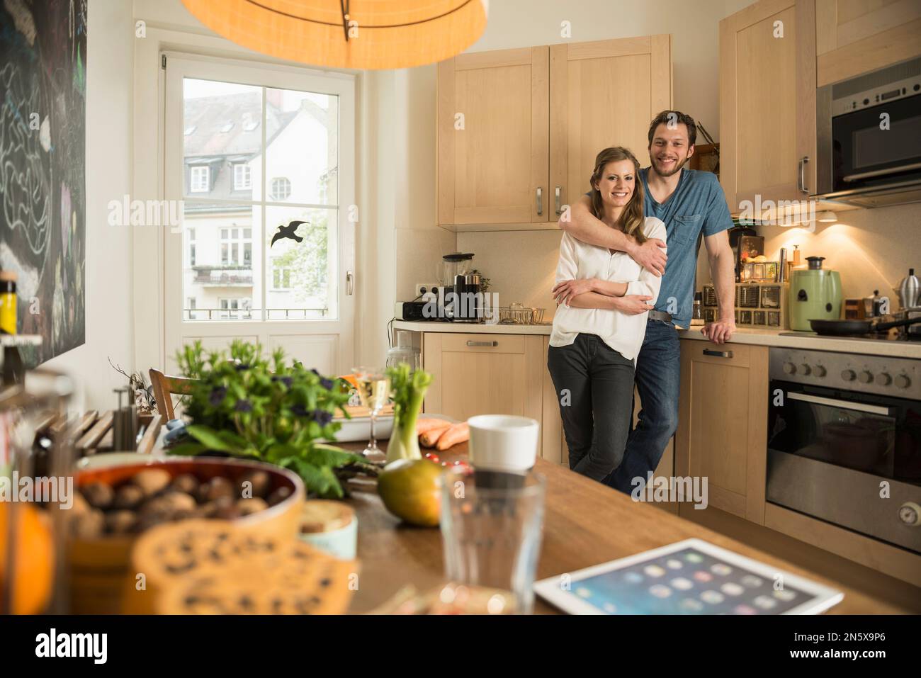 Man hugging his wife in the kitchen, Munich, Bavaria, Germany Stock Photo