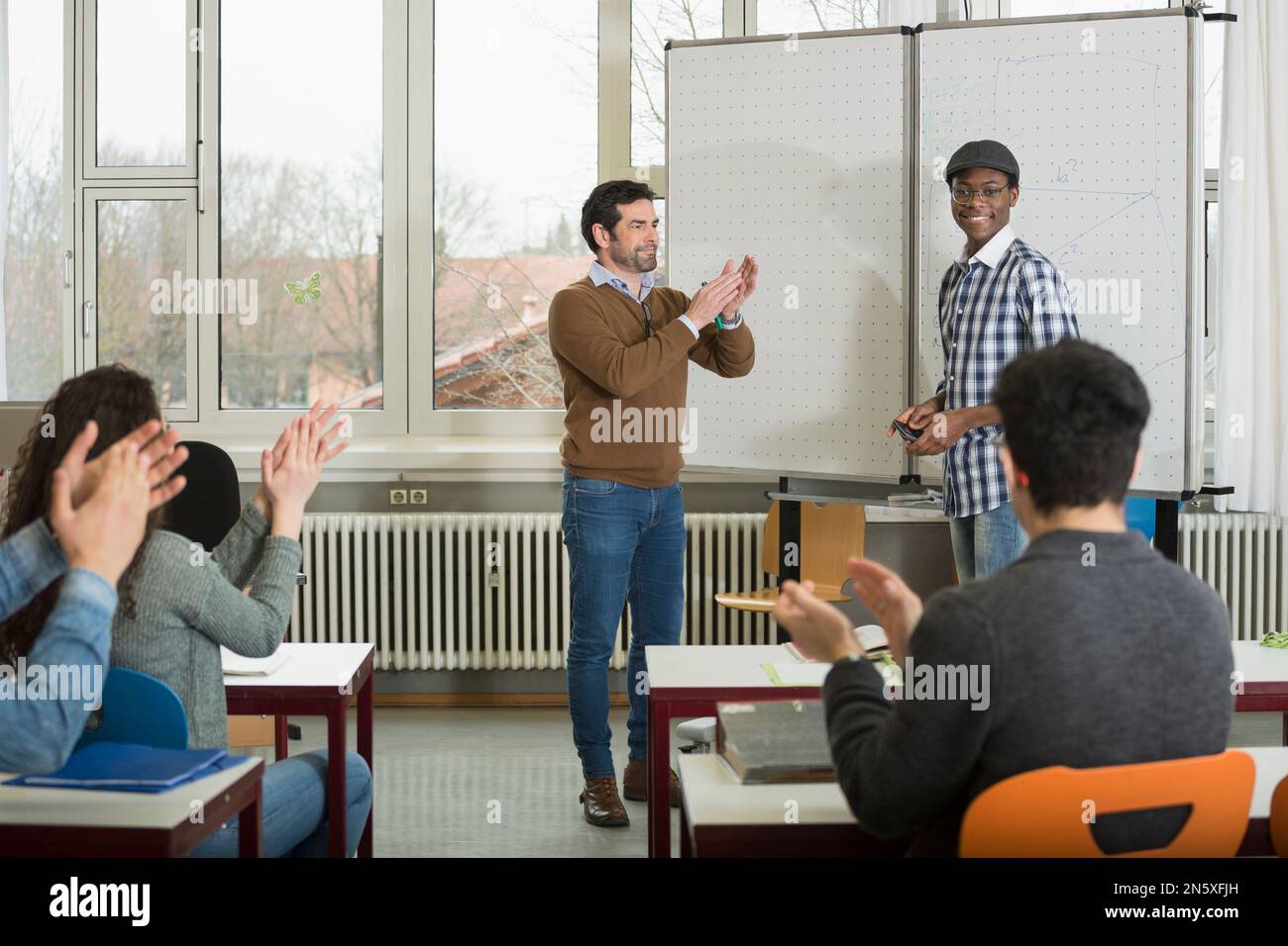 University student finishing classroom presentation, students and teacher clapping School, Bavaria, Germany Stock Photo