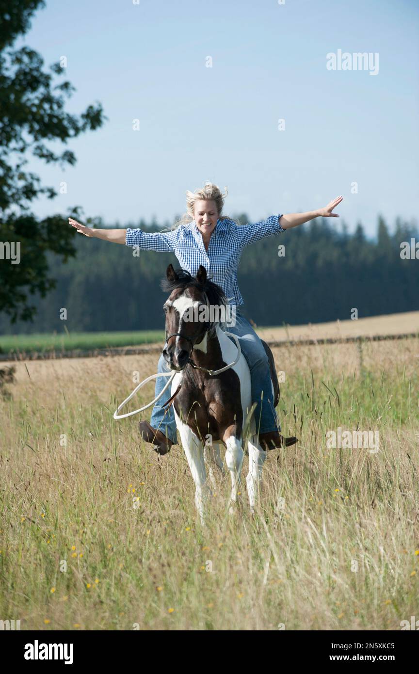 Mid adult woman riding galloping horse without holding reins in the farm, Bavaria, Germany Stock