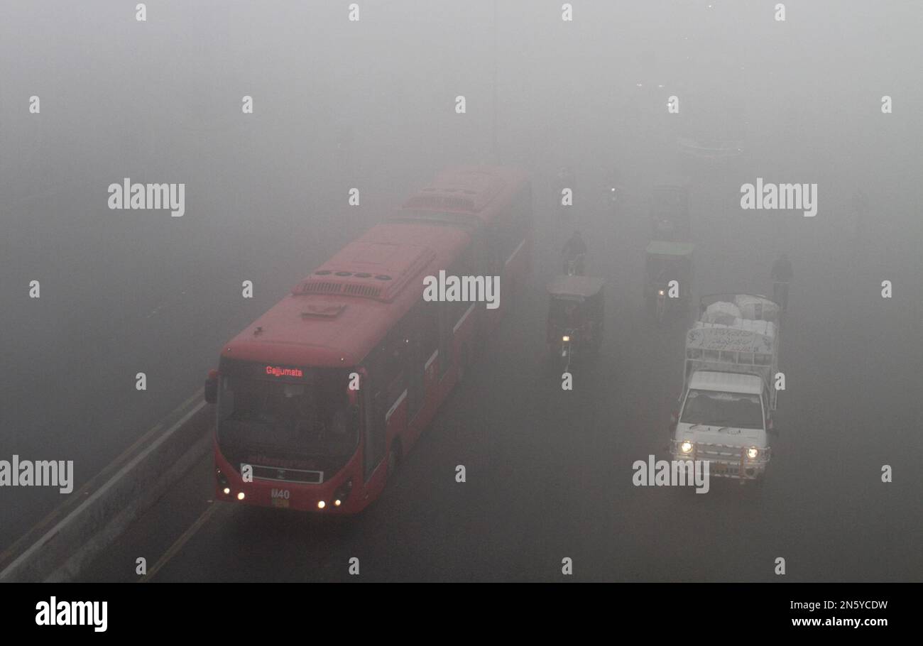 Motorists drive with headlights as fog envelopes Lahore, Pakistan, on