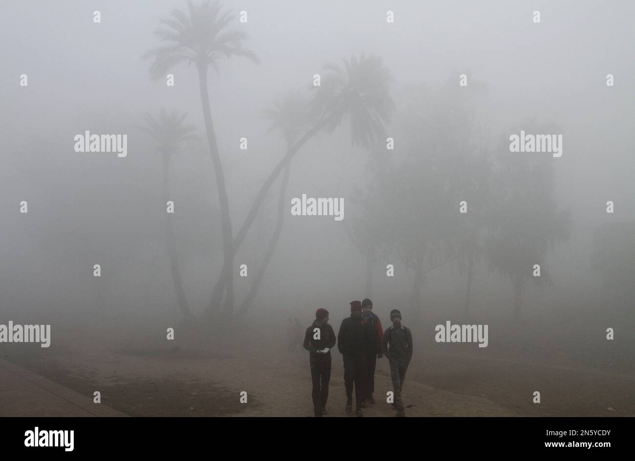 Pakistani students walk together while on their way to school as fog