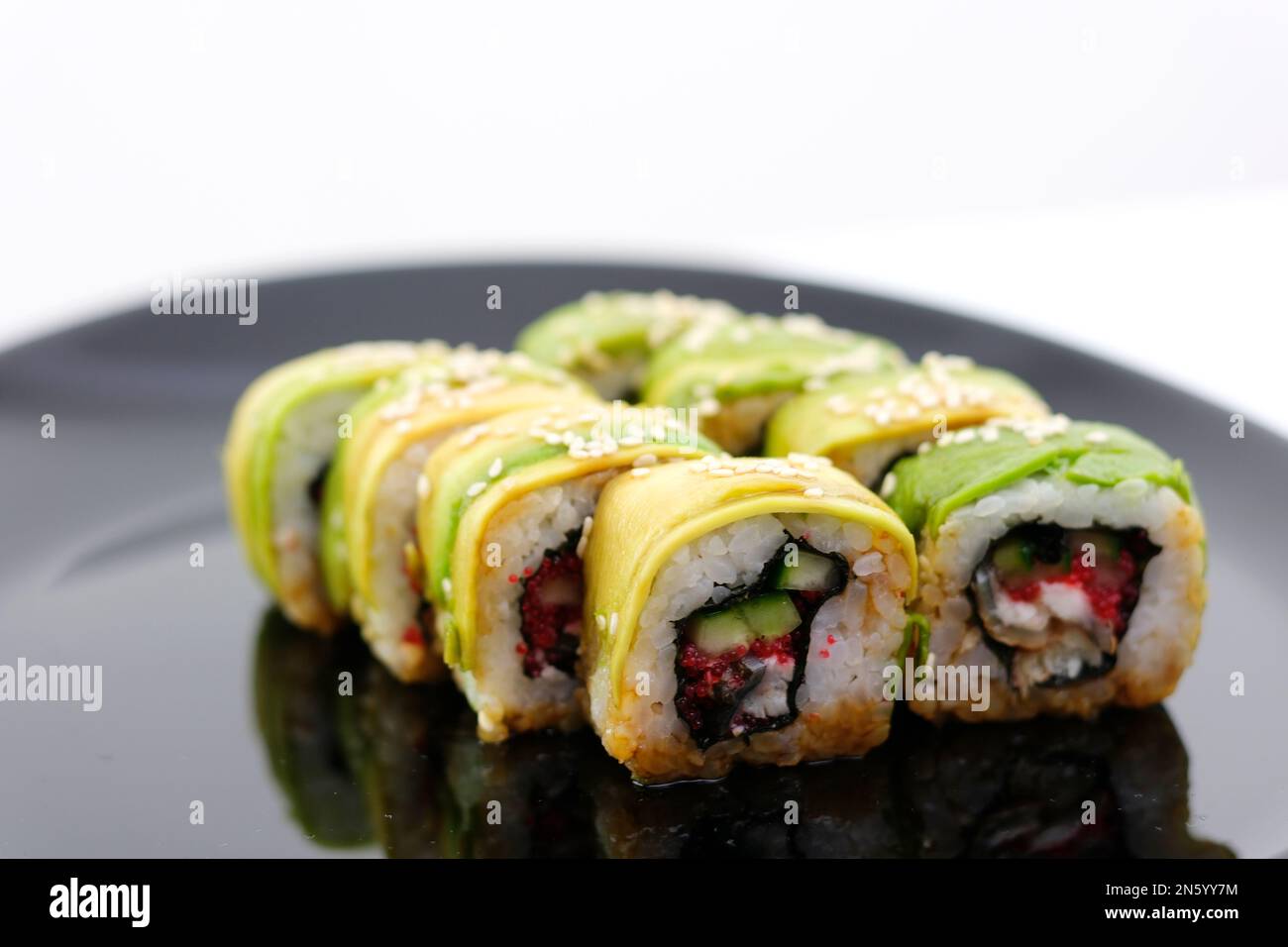 Menu green dragon Japanese rolls with avocado, omelet, sesame and cucumber closeup on a plate on the table. horizontal On a black plate restaurant beautiful serving delicious food japanese chinese Stock Photo