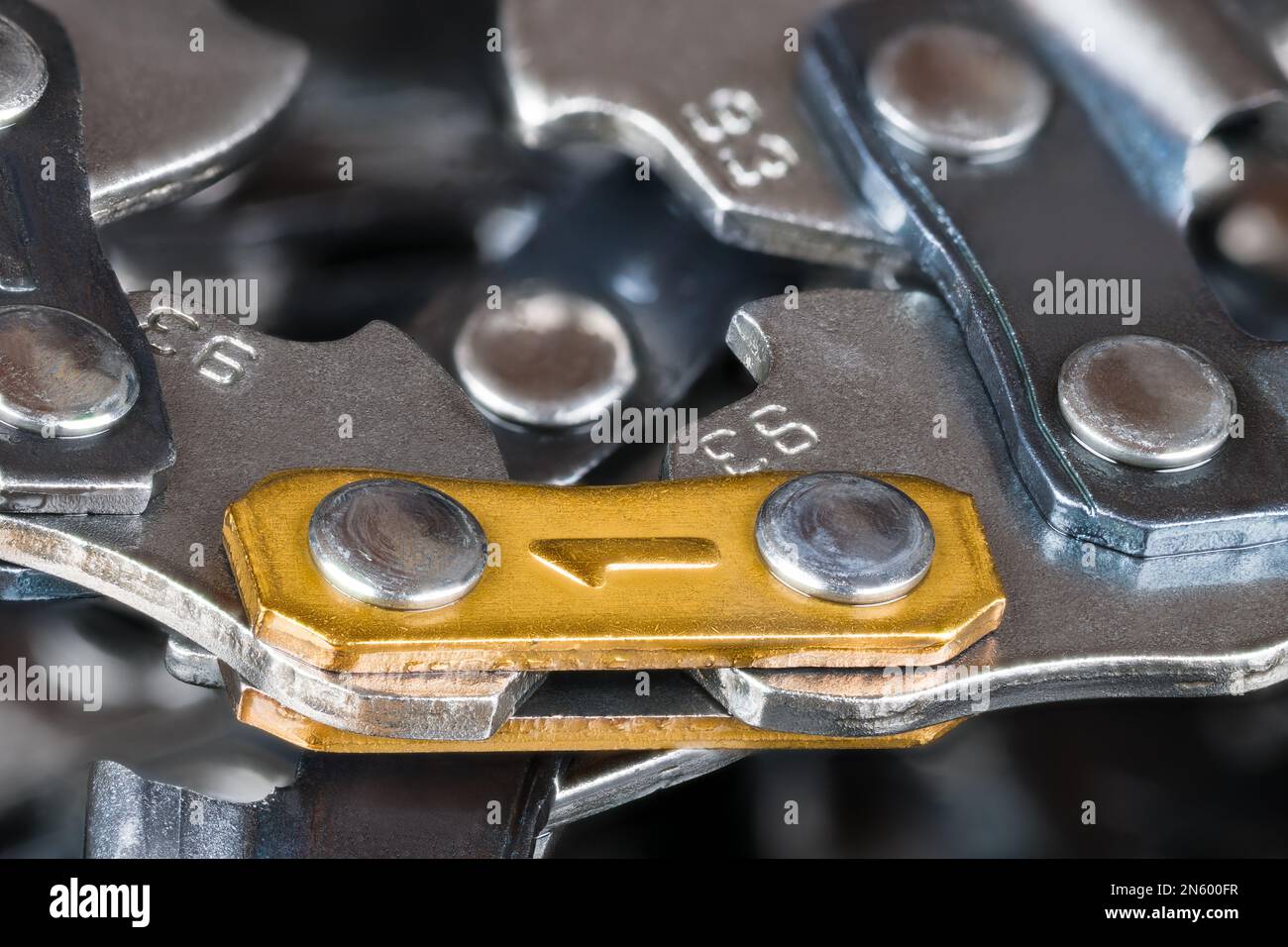 Closeup of cutting chain from metal links joined by rivets for portable chainsaw guide bar. Sharp steel part detail of power tool on blurry background. Stock Photo