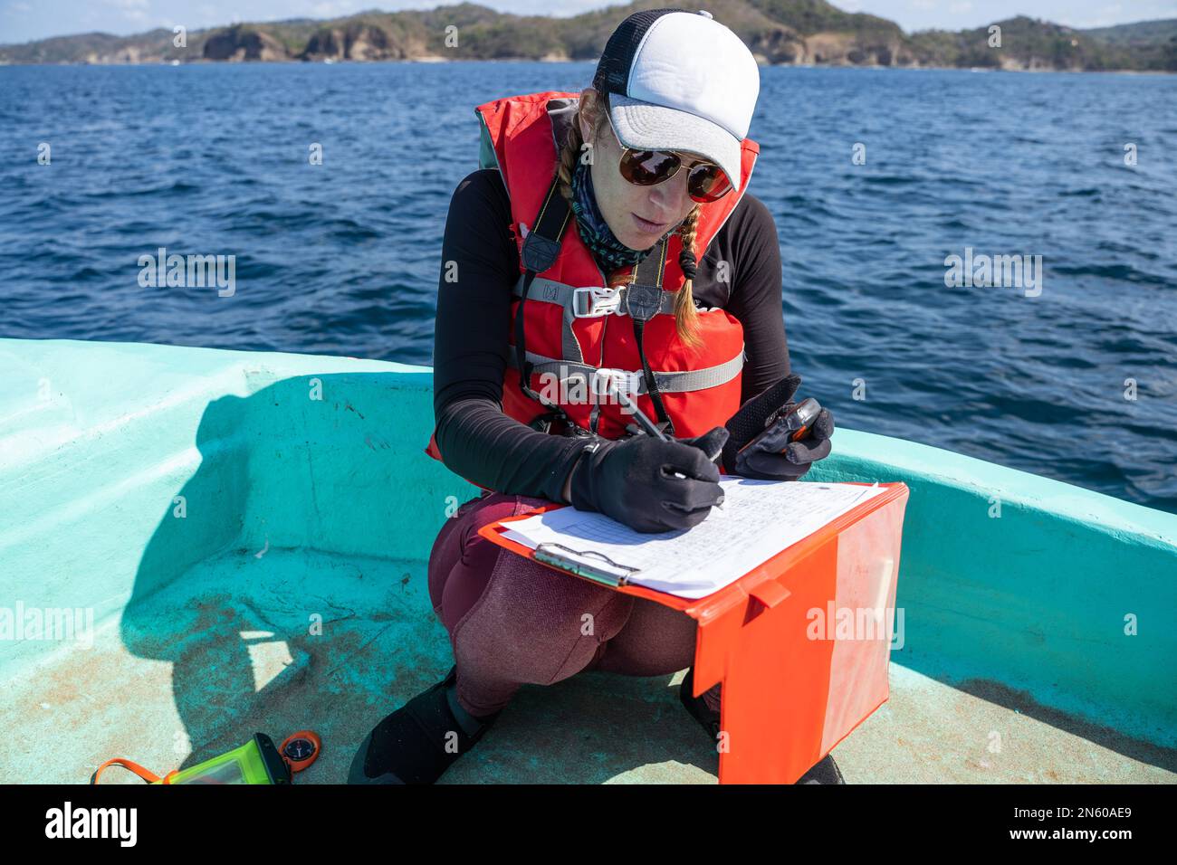 Equipped marine biologist writing notes on a paper while working on a
