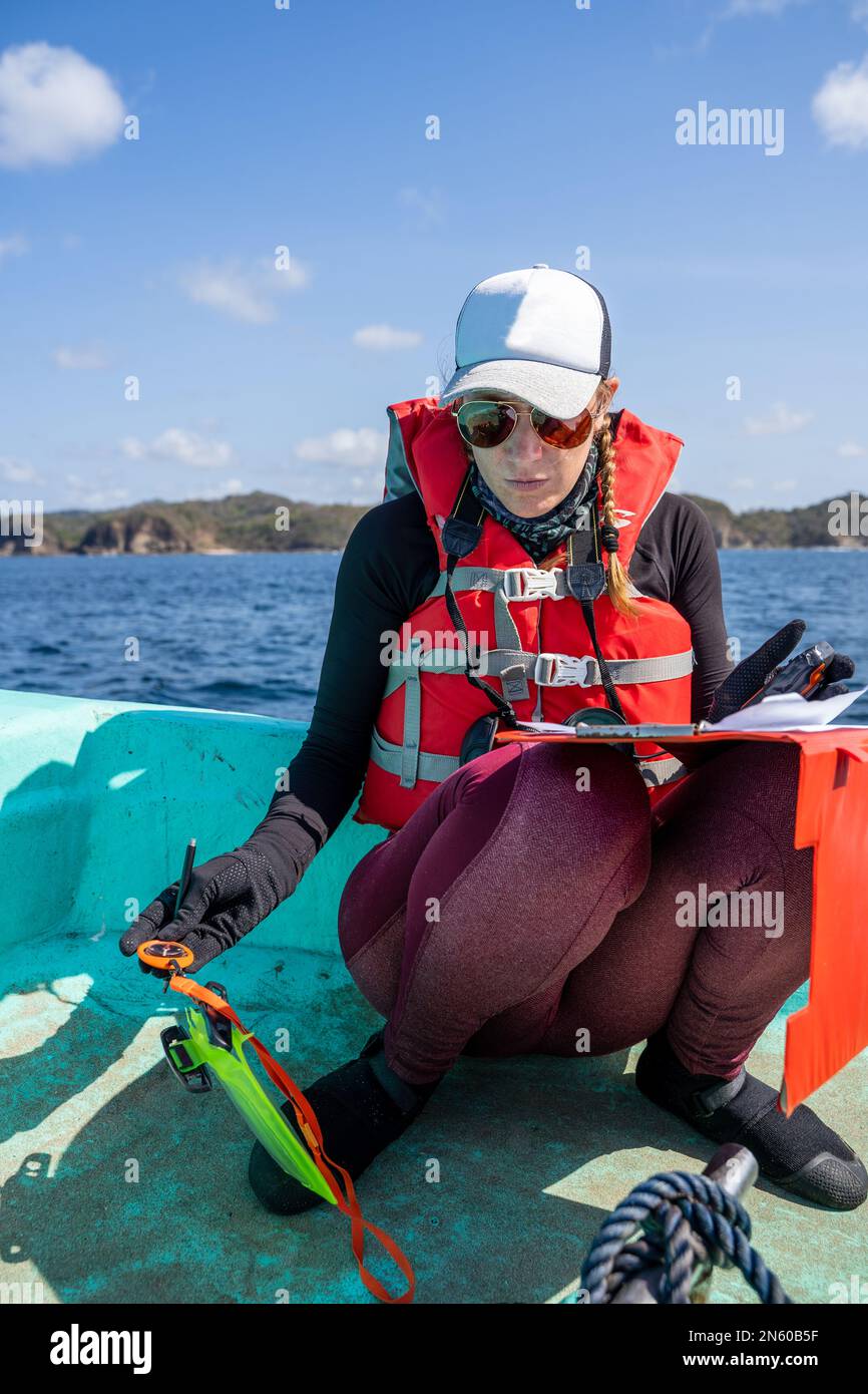 Vertical photo of a equipped marine biologist writing notes on a paper