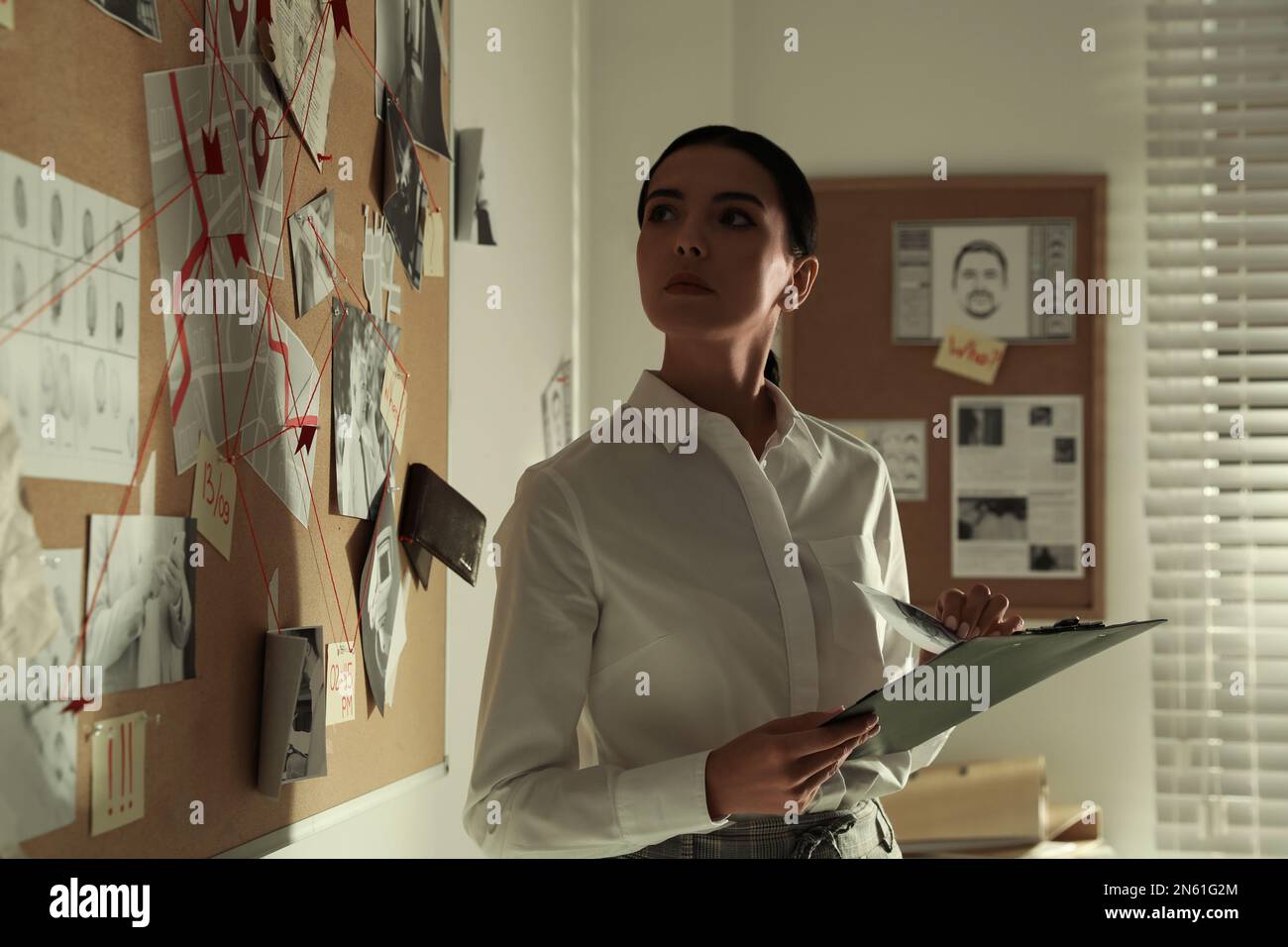 Detective looking at evidence board in office Stock Photo