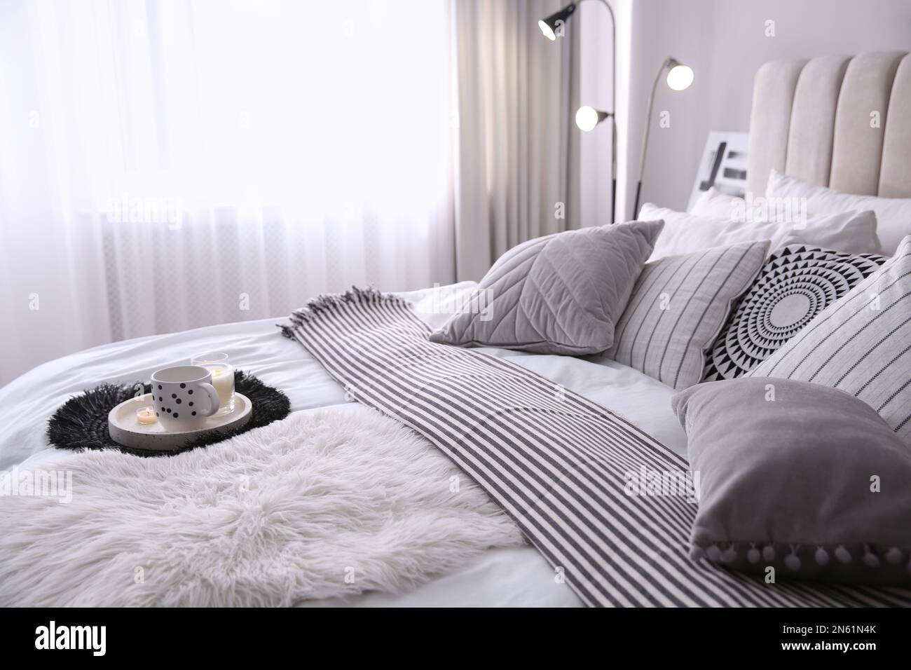 Bed with cushions and striped blanket in room. Interior design Stock Photo