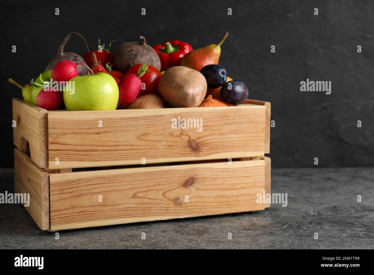 Wooden crate full of different vegetables and fruits on grey table ...