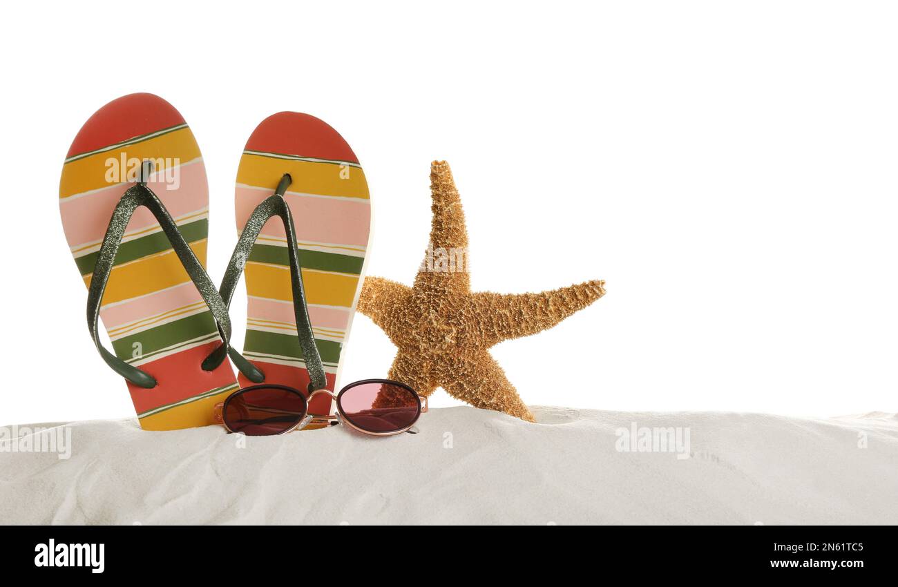 Sunglasses, flip flops and starfish on sand against white background ...