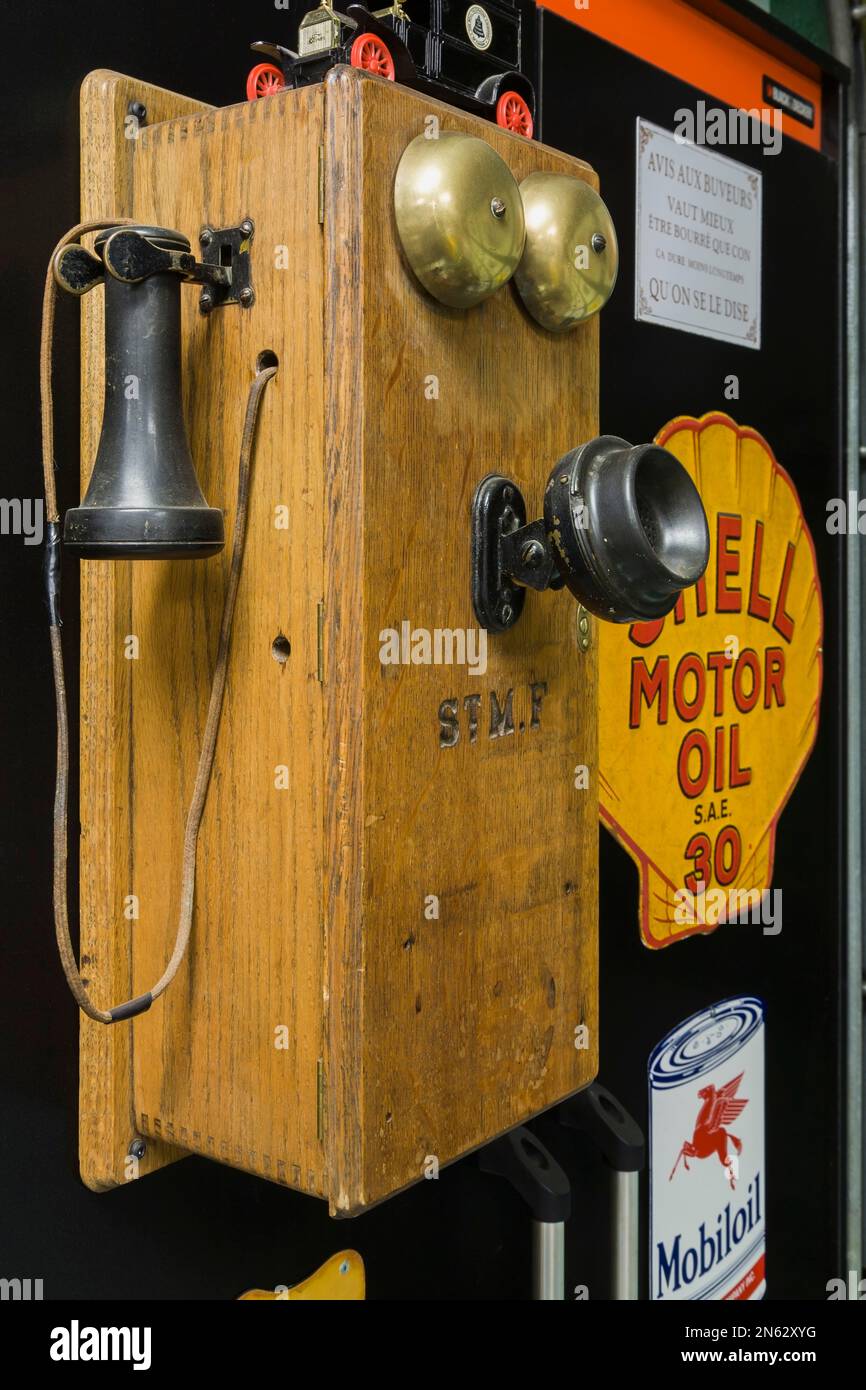 Antique circa 1910 oak wood and black bakelite plain front wall mounted telephone with brass ringing bells in garage inside old 1927 home. Stock Photo