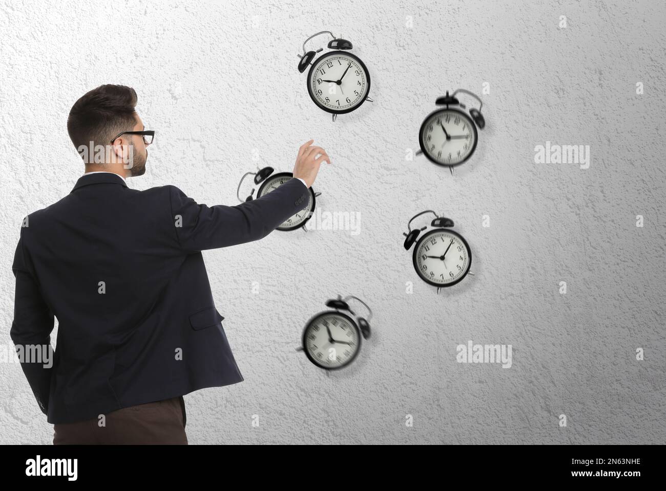 Time management concept. Businessman stretching hand to falling alarm