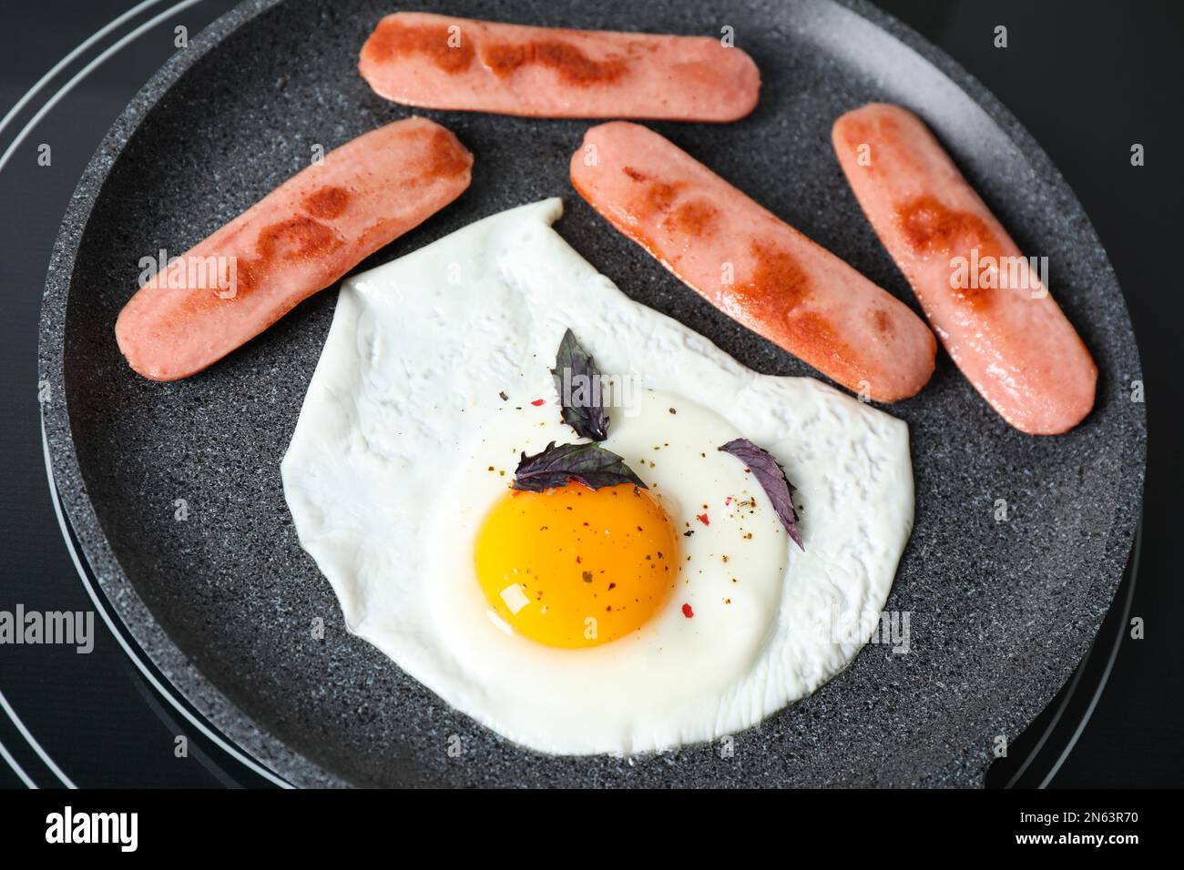 Egg and sausages in frying pan on stove, closeup Stock Photo Alamy