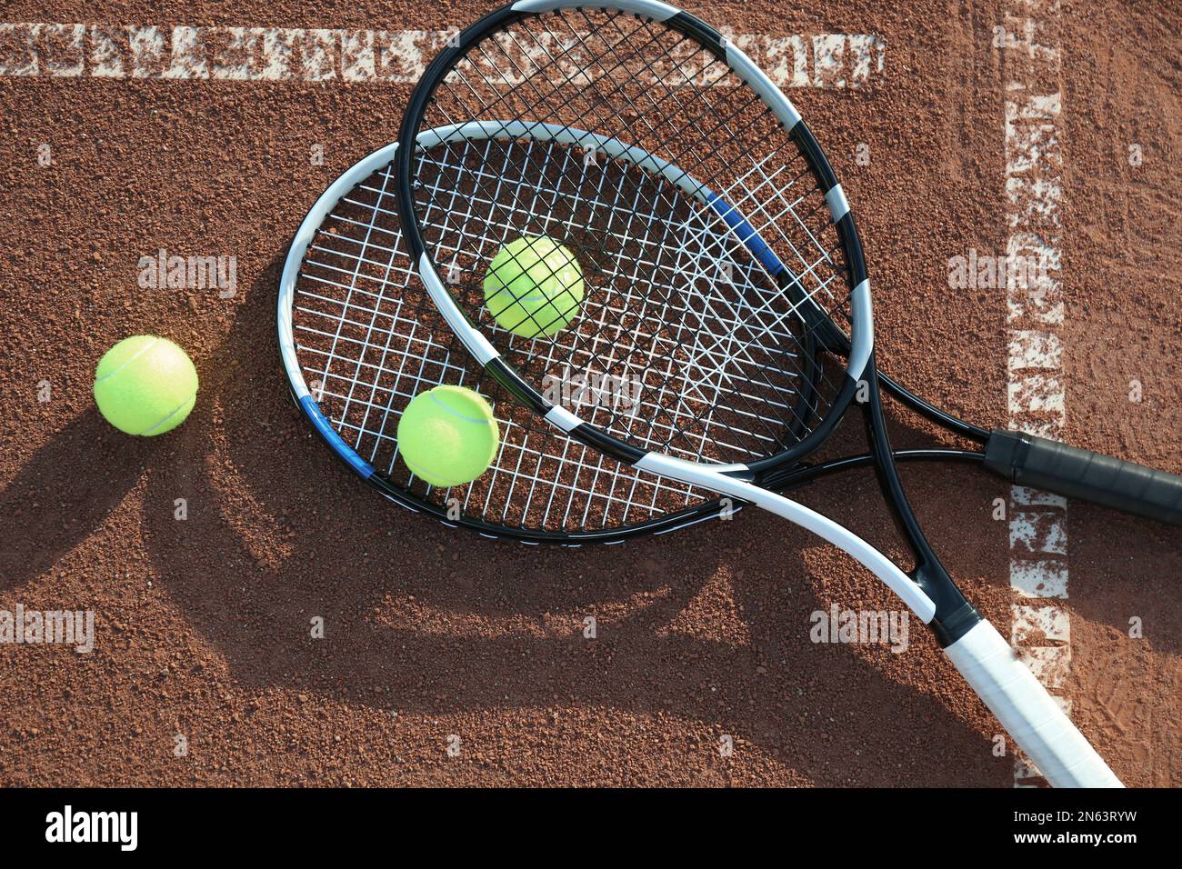 Tennis balls and rackets on clay court, flat lay Stock Photo - Alamy