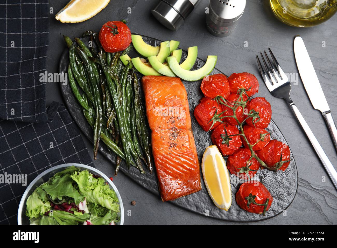 Tasty cooked salmon and vegetables served on black table, flat lay ...