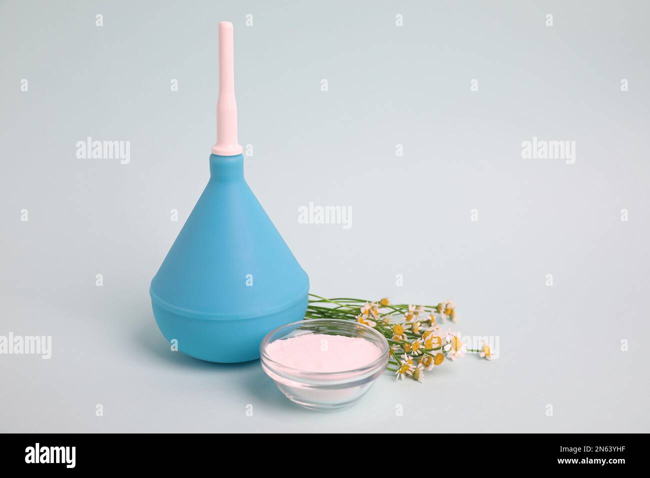 Enema, flowers and bowl of salt on grey background. Medical treatment
