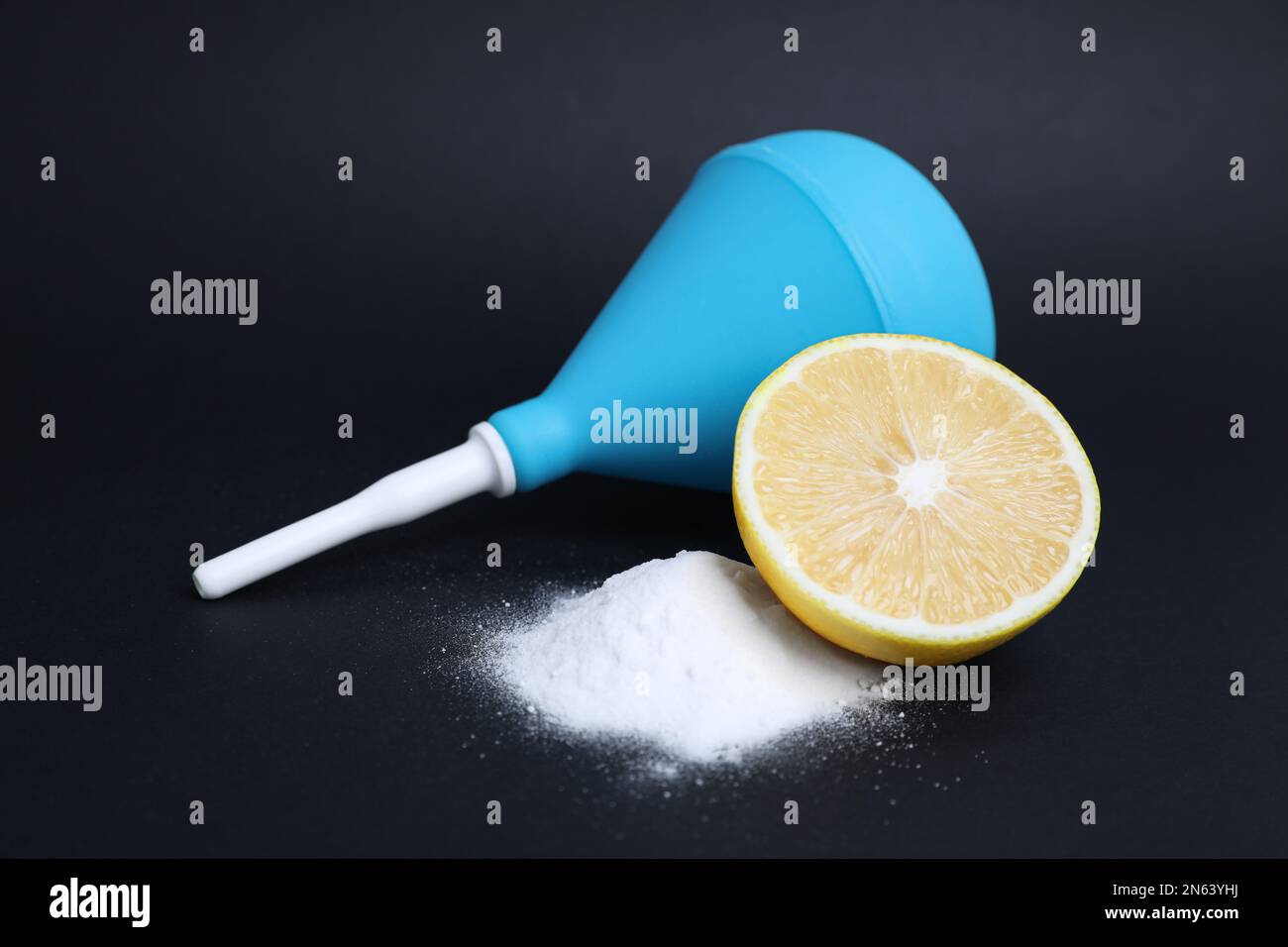 Enema, lemon and heap of salt on black background. Medical treatment