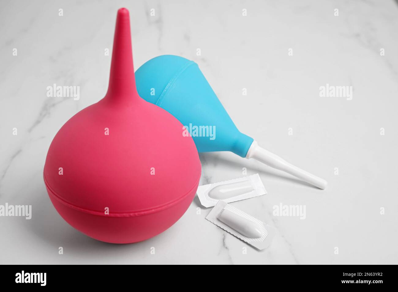 Different enemas and suppositories on white table. Medical treatment