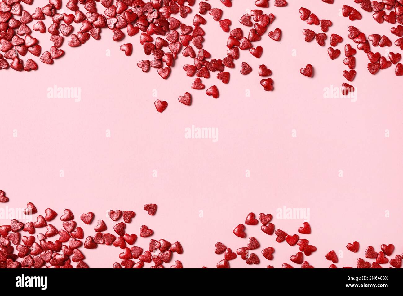 Red heart shaped sprinkles on pink background, flat lay. Space for text