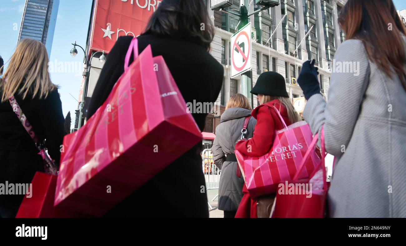 Shoppers carry Victoria Secret bags while crossing an intersection