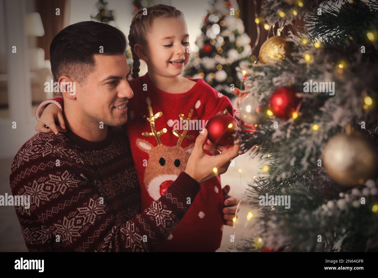 Happy father with his cute daughter decorating Christmas tree together ...