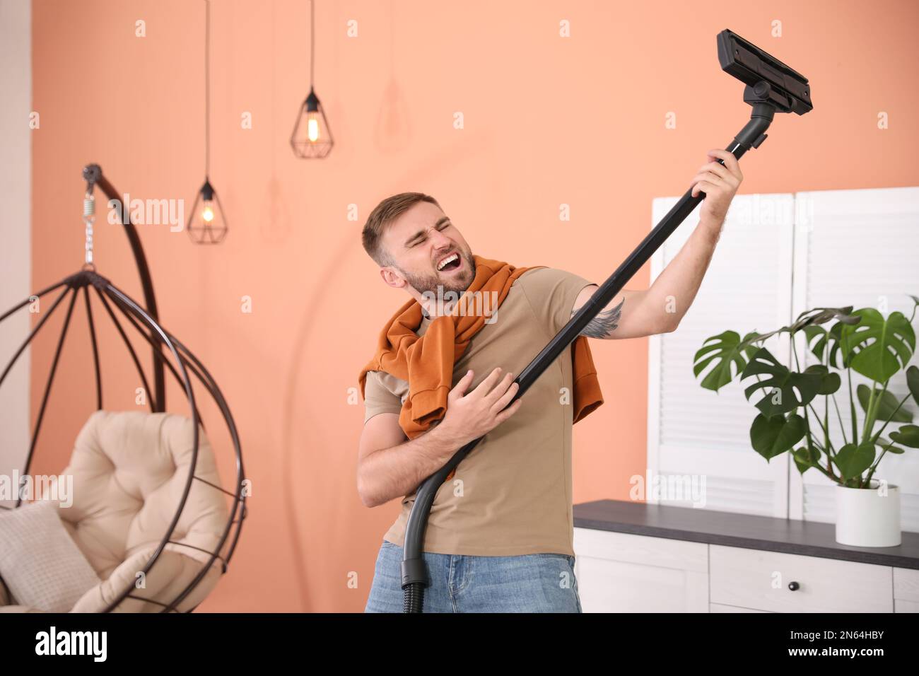 Young man having fun while vacuuming at home Stock Photo