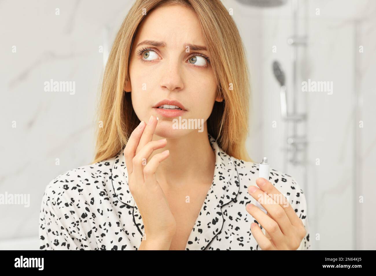 Woman with herpes applying cream onto lip in bathroom Stock Photo Alamy