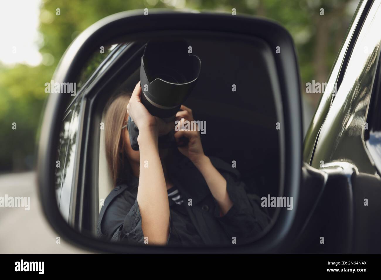 Private detective with camera spying from auto, view through car side