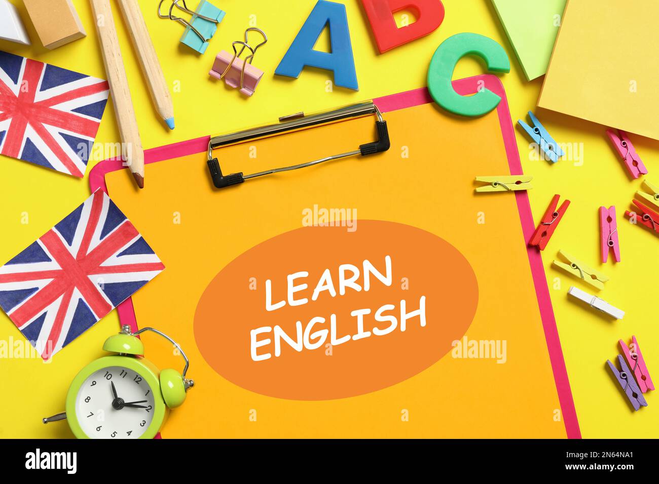 Clipboard with phrase Learn English and stationery on yellow background