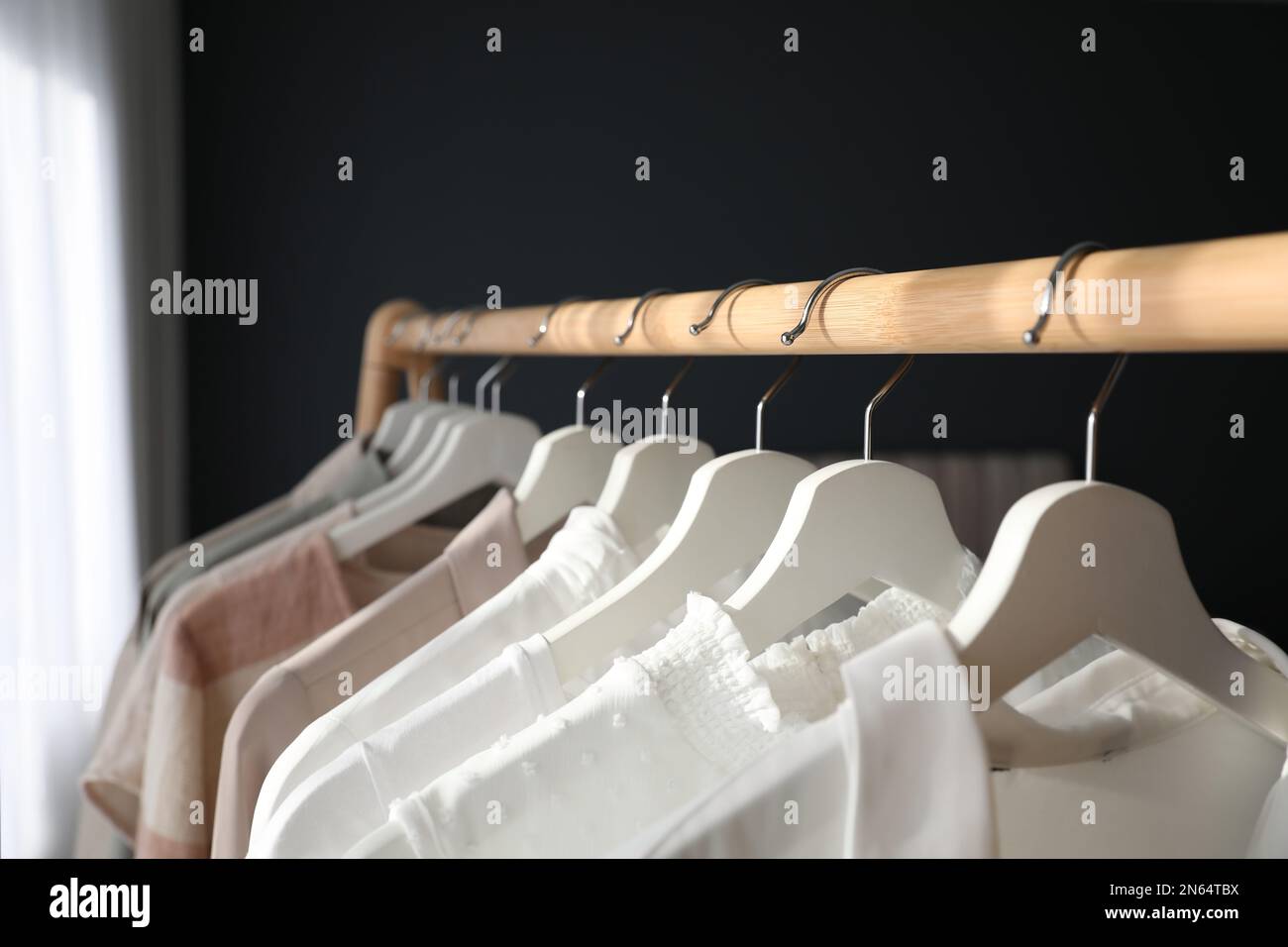 Different stylish clothes on rack indoors, closeup Stock Photo
